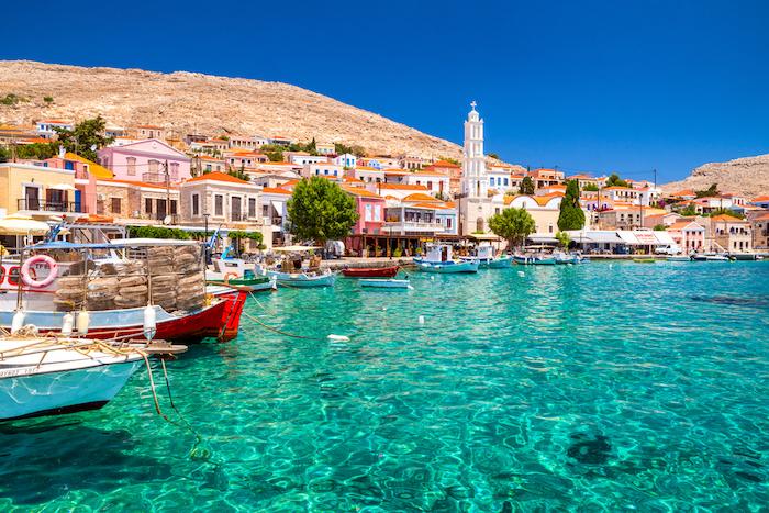 The Best Things to Do When Travelling in Greece. Halki, Greece - July 6, 2022: Colorful houses and fishing boats in picturesque small island Halki (Chalki) in Greece